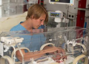 Krankenpflegerin berührt Frühchen in Inkubator