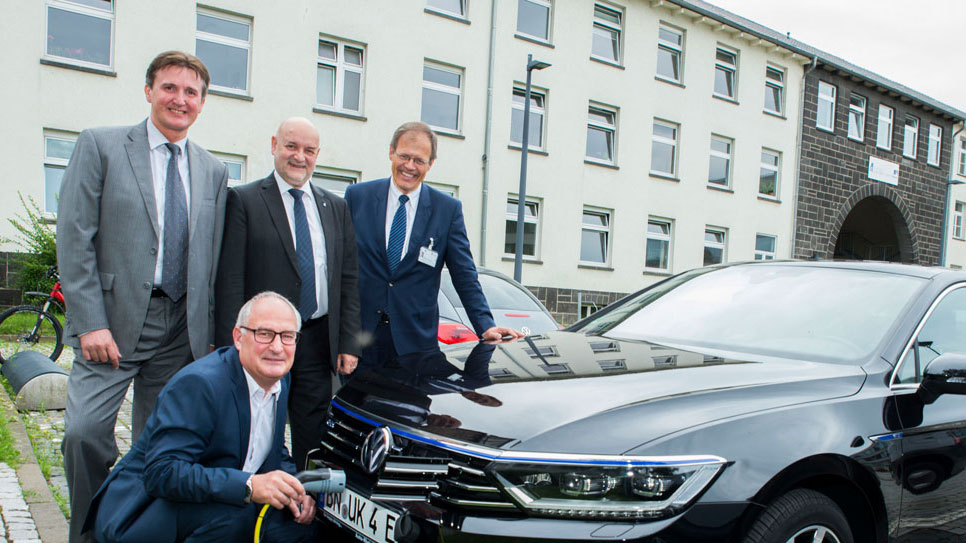 Der Fahrer des Universitätsklinikums Bonn Karl-Heinz Lohmer lädt den neuen Elektro- Dienstwagen des Uniklinikums Bonn. Die Vorstandmitglieder Prof. Wolfgang Holzgreve, Damian Grüttner und Alexander Pröbstl freuen sich