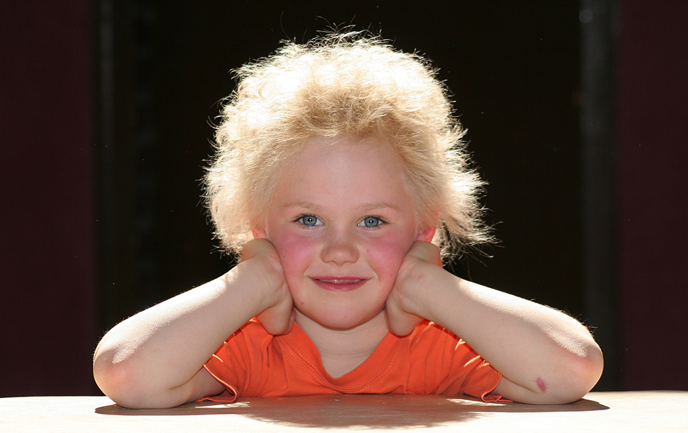 Kind mit vielen blonden zerzausten Haaren