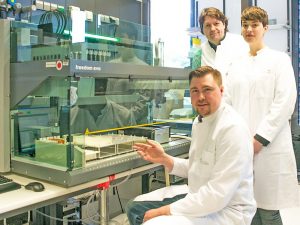 Das Forscherteam am Pipettierroboter in der Abteilung für Genomik des Life & Brain Forschungszentrums: Dr. Andreas Forstner (sitzend vorne), Privatdozent Dr. Rupert Conrad und Psychologin Stefanie Rambau (stehend von links)