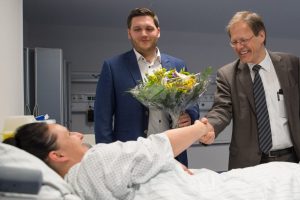 Prof. Wolfgang Holzgreve, Ärztlicher Direktor und Vorstandsvorsitzender am UKB, und Thorsten Trinks, OP-Koordinator am UKB, begrüßen die erste Patientin bei der offiziellen Inbetriebnahme der Patientenholding Area am UKB.