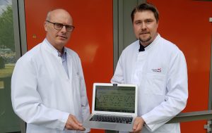 Prof. Dr. Markus M. Nöthen (links) und Dr. Andreas Forstner mit einer Abbildung, wie verschiedene psychische Erkrankungen genetisch zusammenhängen.