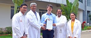 Dr. Maximilian Wintergerst (Mitte) präsentiert zusammen mit den Kollaborationspartnern des Sankara Eye Hospital in Bangalore Dr. Kaushik Murali (2. v. li), Dr. Mahesh Shanmugam (2. v. re), Dr. Divyansh Mishra (1. v. re) und Dr. Payal Shah (1. v. li) den Fördervertrag