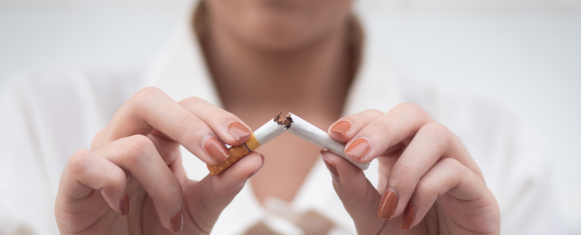 Frauenhände beim Durchbrechen einer Zigarette