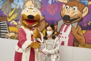 Maskottchen Bonni der Telekom Baskets Bonn schenkt der kleinen Amira, Patientin im ELKI des UKB, einen Schokonikolaus und eine Kinderalltagsmaske.