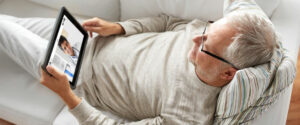 Mann liegt mit Tablet auf Couch