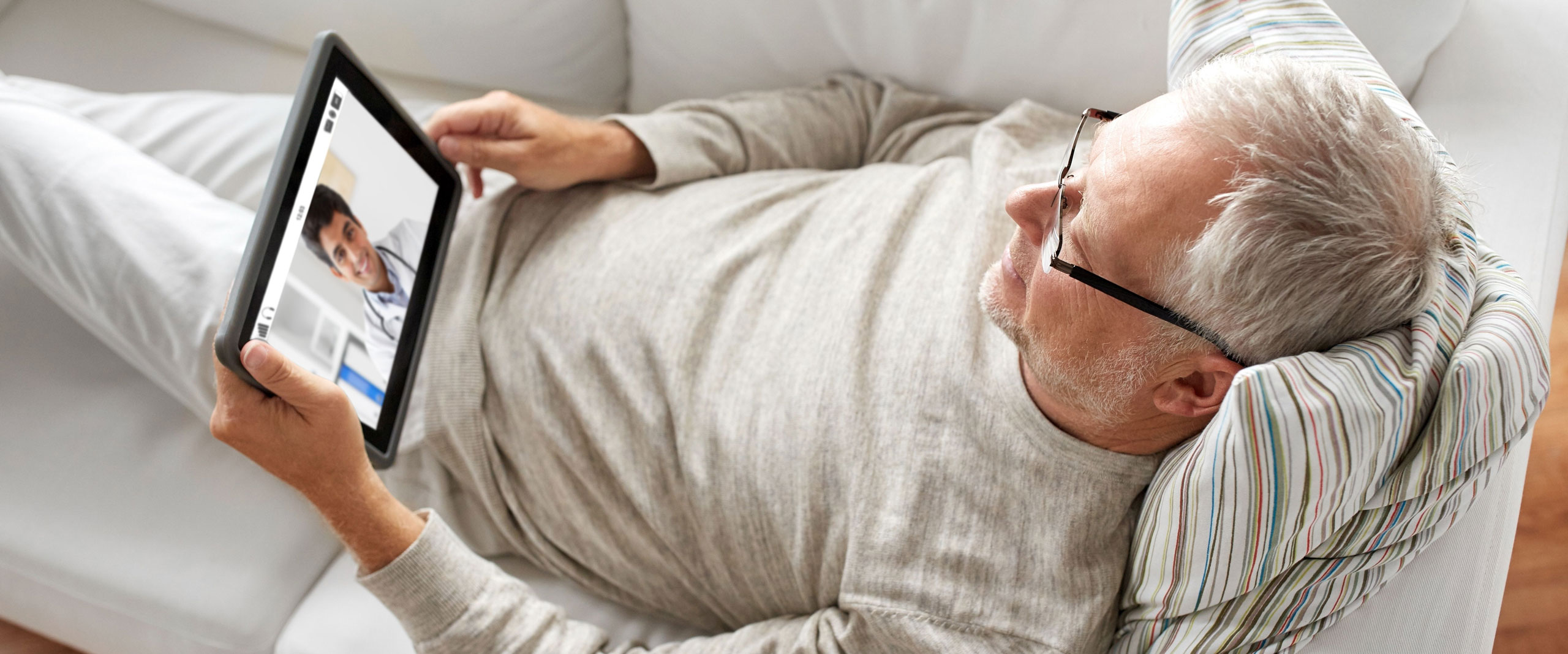 Mann liegt mit Tablet auf Couch