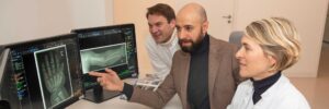Prof. Dr. Peter Krawitz (li) und Dr. Behnam Javanmardi (Mitte) diskutieren Knochenmerkmale mit Dr. Martha Dohna, Expertin für Kinderradiologie am UKB.