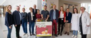 Prof. Alexandra Philipsen (4. v. l.) und die Mitarbeiterinnen der Kinderonkologie des UKB begrüßen Dr. Hanns-Christoph Eiden, Präsident des Rotary Clubs Bonn (2. v. l.), sowie weitere Vertreterinnen und Vertreter der Rotary Clubs zum gemeinsamen Besuch mit Fruchtalarm im UKB.