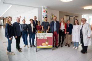 Prof. Alexandra Philipsen (4. v. l.) und die Mitarbeiterinnen der Kinderonkologie des UKB begrüßen Dr. Hanns-Christoph Eiden, Präsident des Rotary Clubs Bonn (2. v. l.), sowie weitere Vertreterinnen und Vertreter der Rotary Clubs zum gemeinsamen Besuch mit Fruchtalarm im UKB.