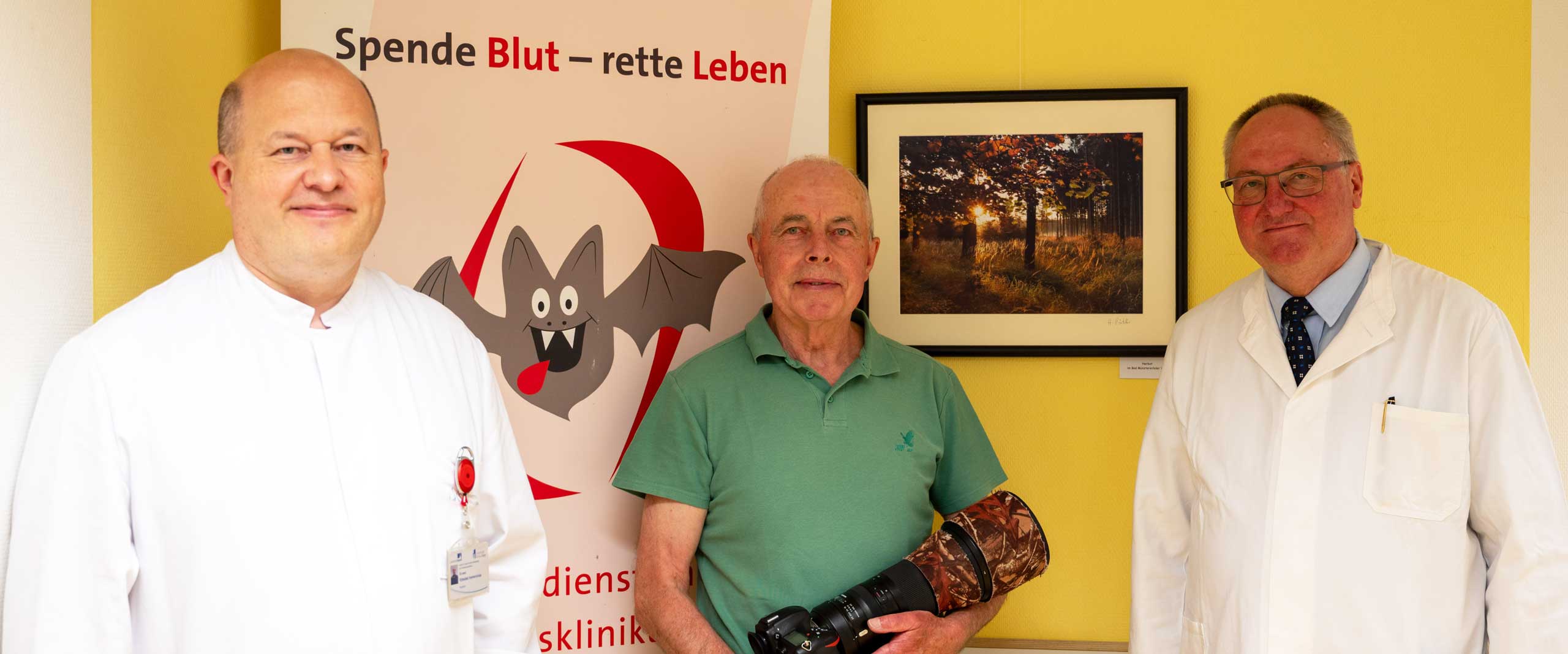 PD Dr. med. Vytautas Ivaskevicius, Oberarzt Institut für Experimentelle Hämatologie und Transfusionsmedizin (IHT), Fotograf Heinrich Pützler und Prof. Dr. Johannes Oldenburg, komm. stellv. Ärztlicher Direktor und Direktor des IHT am UKB, bei der Eröffnung der Ausstellung im Gebäude des Blutspendedienstes am UKB.