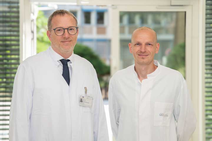 Prof. Dr. Dr. Franz-Josef Kramer, Direktor der Klinik für Mund-, Kiefer- und Plastische Gesichtschirurgie des UKB, und Dr. Tim Klünter, Oberarzt und Sektionsleiter Oralchirurgie, informieren im Patientenkolloquium über Ursachen, Risiken und moderne Behandlungswege bei entzündeten Zahnimplantaten.